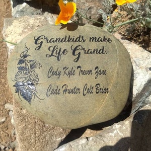 May include: A gray stone with the words "Grandkids make life grand." and a floral design. Below the text are the names Cody, Kyle, Trevor, Zane, Cade, Hunter, Colt, and Briar.