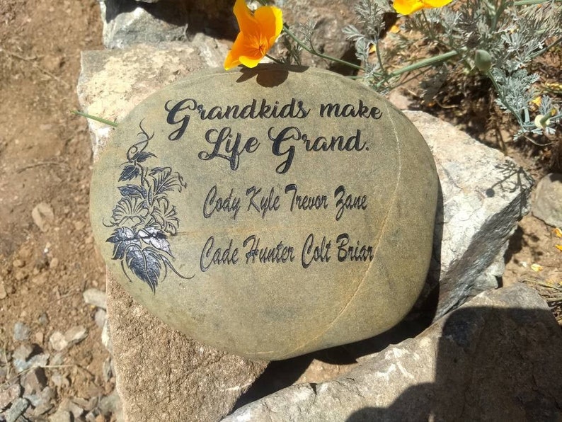 May include: A gray stone with the words "Grandkids make life grand." and a floral design. Below the text are the names Cody, Kyle, Trevor, Zane, Cade, Hunter, Colt, and Briar.