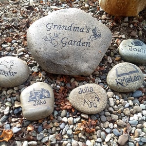 May include: A collection of six personalized stones with various designs and names, including "Grandma's Garden", "Taylor", "Jake", "Kristen", "Josh", and "Julia".