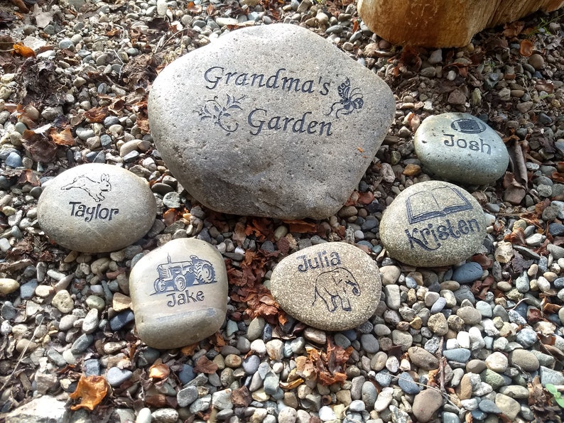 May include: A collection of six personalized stones with various designs and names, including "Grandma's Garden", "Taylor", "Jake", "Kristen", "Josh", and "Julia".