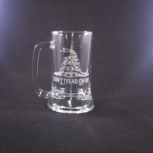 May include: A clear glass beer stein with a white etched image of a coiled snake with the words "Don't Tread On Me".