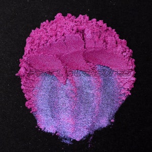 May include: A close-up of a pile of iridescent purple and pink mica powder. The powder is shimmery and has a fine texture.