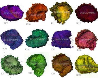 May include: Twelve piles of loose, shimmering pigment powder arranged in a grid, each labeled with codes IC9 through IC20 and the brand name KOLOREFX. The powders display metallic, color-shifting hues including purple, orange, green, red, and gold.