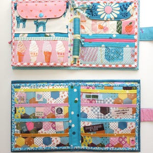 K&ouml;nnte beinhalten: Ein handgefertigter Stoff-Organizer mit mehreren Taschen und F&auml;chern. Der Organizer weist verschiedene Muster auf, darunter Eiswaffeln, Katzen und florale Designs. Er hat einen blauen Rei&szlig;verschluss und einen rosa Bandverschluss. Der Innenraum enth&auml;lt kleine Etiketten mit Text.
