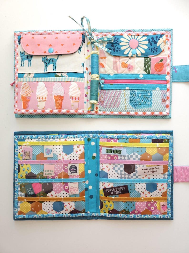 K&ouml;nnte beinhalten: Ein handgefertigter Stoff-Organizer mit mehreren Taschen und F&auml;chern. Der Organizer weist verschiedene Muster auf, darunter Eiswaffeln, Katzen und florale Designs. Er hat einen blauen Rei&szlig;verschluss und einen rosa Bandverschluss. Der Innenraum enth&auml;lt kleine Etiketten mit Text.