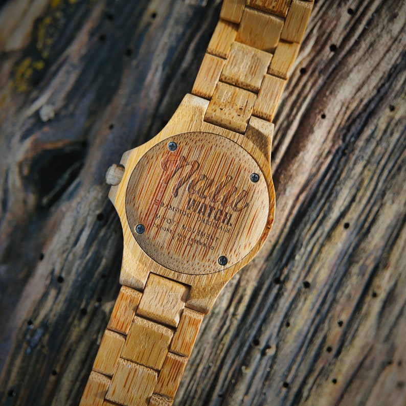 May include: A wooden wristwatch with a brown bamboo band and a round face. The face has a black background with the words "Maller Watch" printed in white.
