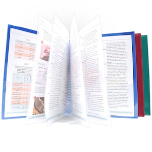 May include: A blue, red, and green binder with a spiral binding. The binder is open to a page with text and diagrams. The text includes instructions for crocheting. The page also includes a table with yarn colors and their corresponding codes.