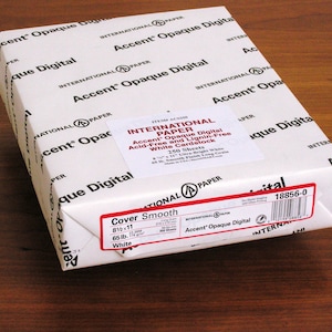 K&ouml;nnte beinhalten: Eine wei&szlig;e Schachtel mit Accent Opaque Digital Papier. Die Schachtel ist mit dem Produktnamen, der Gr&ouml;&szlig;e, dem Gewicht und der Menge beschriftet. Die Schachtel befindet sich auf einer Holzoberfl&auml;che.
