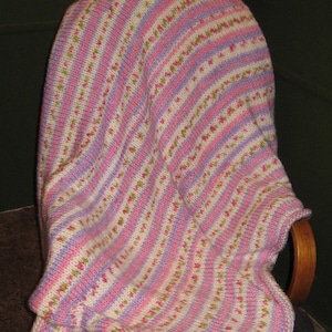 May include: A pink and white striped knitted blanket draped over a wooden rocking chair.