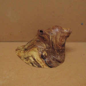 May include: A brown and tan wood sculpture with a unique shape and intricate grain patterns.