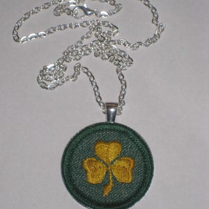May include: A silver chain necklace with a green and gold shamrock pendant.