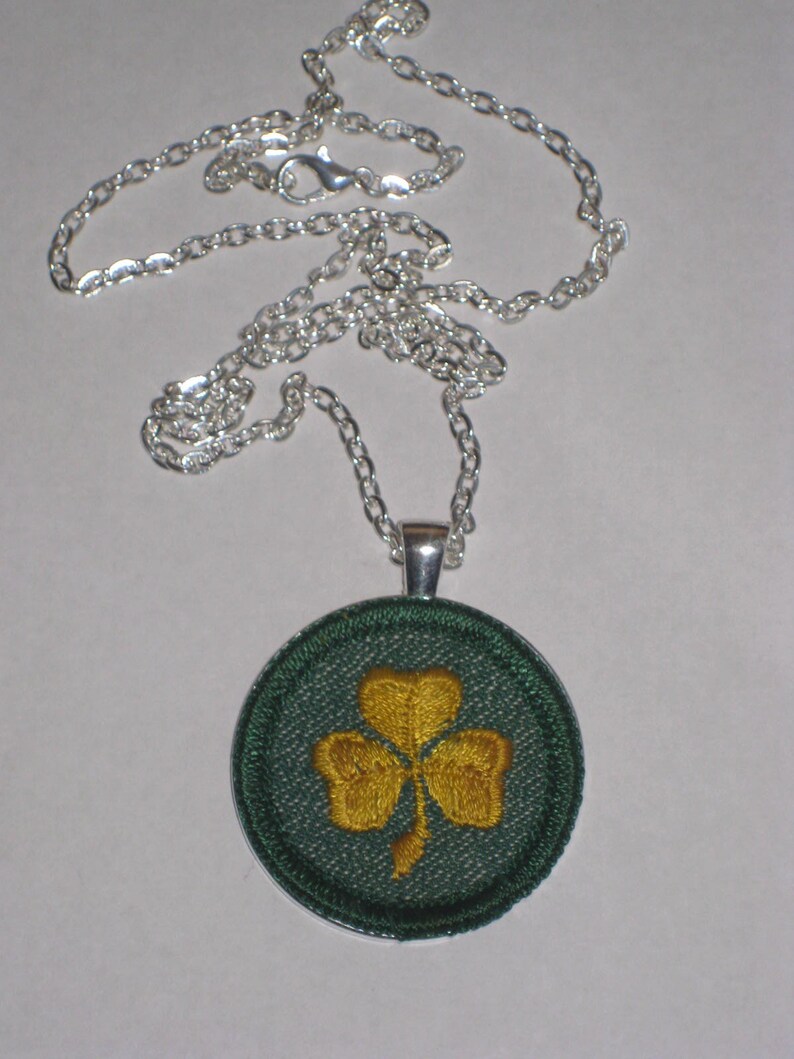 May include: A silver chain necklace with a green and gold shamrock pendant.