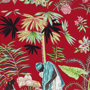 May include: Two people wearing colorful clothing are standing in front of a red background with a tropical print. They are both holding pottery. The pottery is white with brown accents. The background is a red fabric with a tropical print.