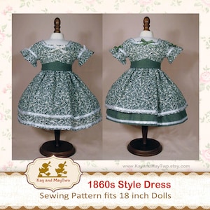May include: Two 1860s style doll dresses on display. The dresses are green with a white leaf pattern, white lace trim, and a green sash. The text on the image reads "1860s Style Dress Sewing Pattern fits 18 inch Dolls."