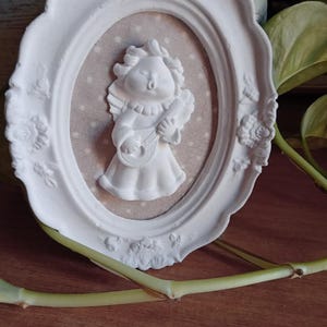 Decorative picture made of ceramic powder with little angel on a cloth background