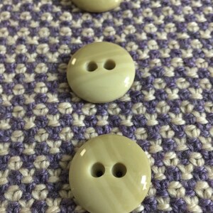 May include: Three beige buttons with two holes each. The buttons are approximately 1 inch in diameter and have a striped pattern.