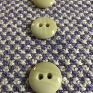 May include: Three beige plastic buttons with two holes each. The buttons are approximately 1 inch in diameter.