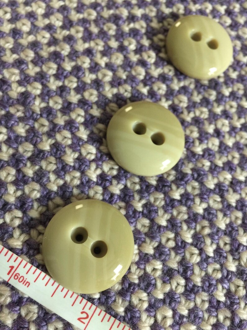 May include: Three light green plastic buttons with two holes each. The buttons have a striped pattern and a glossy finish.