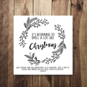 May include: A black and white printable sign with a Christmas wreath design. The text reads "It's beginning to smell a lot like Christmas."  The sign also includes instructions for making a Christmas-scented simmer pot.