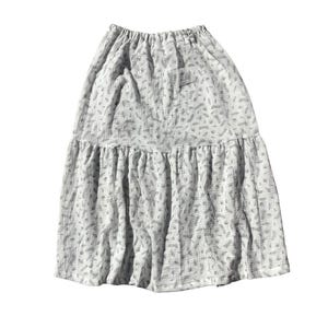May include: A white skirt with a small floral print. The skirt has a tiered design and a gathered elastic waistband.