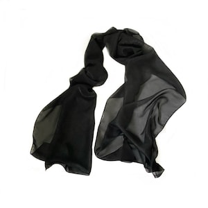May include: A flowing, black scarf made of sheer fabric. The scarf is draped and appears lightweight, with a subtle sheen. The scarf is a solid black color and is likely made of silk or a similar material.