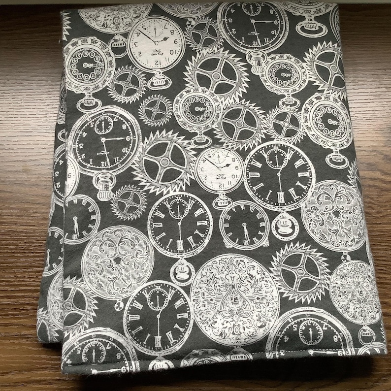 May include: A folded piece of dark grey fabric featuring a repeating white print of various vintage pocket watches, clock faces with Roman and Arabic numerals, and intricate mechanical gear patterns arranged in a dense, overlapping composition.