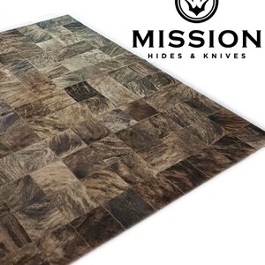 May include: A brown and black cowhide patchwork rug with a square pattern. The rug is made from natural cowhide and has a unique, rustic look.