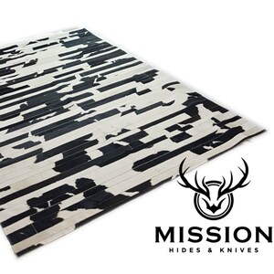 Puede incluir: Alfombra de piel de vaca negra y blanca con un patrón a rayas. La alfombra está hecha de tiras de cuero cosidas juntas. La alfombra está hecha por Mission Hides & Knives.