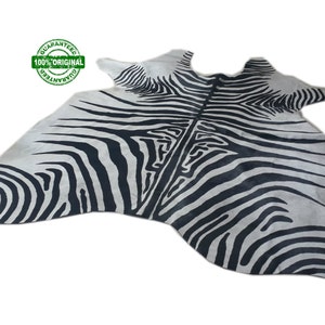 May include: Black and white zebra hide rug. The rug is made of real zebra hide and has a natural, rustic look.