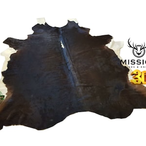 May include: A brown and white cowhide rug with a natural, distressed look. The rug is large and has a unique pattern. The rug is 100% original and guaranteed.