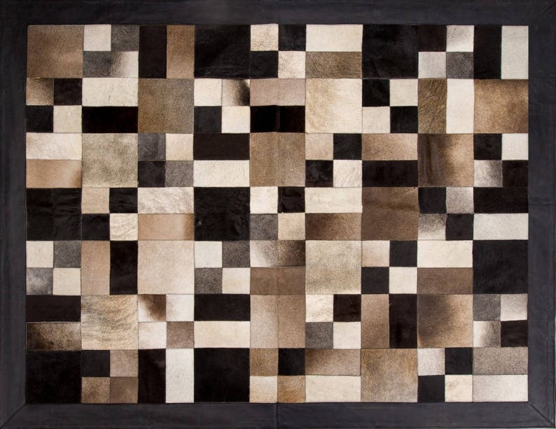 May include: A black and white patchwork rug made of cowhide. The rug is made up of squares of different sizes and colours. The rug is perfect for adding a touch of rustic charm to any room.