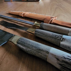 Puede incluir: Un juego de tres cuchillos de cocina con mangos de madera y detalles en lat&oacute;n. Los cuchillos incluyen un cuchillo de chef, un cuchillo para trinchar y un tenedor.