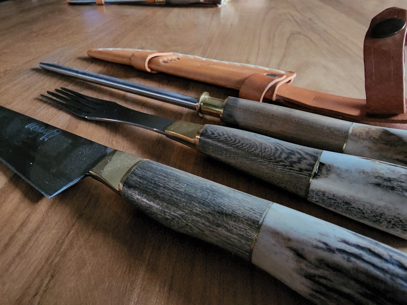 Puede incluir: Un juego de tres cuchillos de cocina con mangos de madera y detalles en lat&oacute;n. Los cuchillos incluyen un cuchillo de chef, un cuchillo para trinchar y un tenedor.