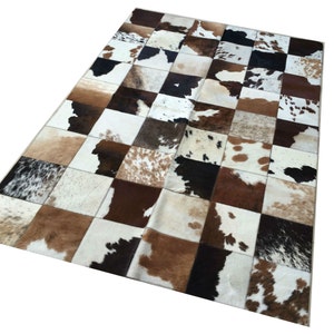 Op de afbeelding: Een rechthoekig patchwork kleed met een dambordpatroon. Het kleed is samengesteld uit vierkanten van koeienhuid in bruin, wit en zwart. Het patroon van het kleed cre&euml;ert een textuurrijk oppervlak, geschikt voor interieurdecoratie.