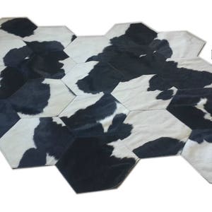 Puede incluir: Alfombra de piel de vaca negra y blanca hecha de piezas hexagonales. La alfombra está hecha de piel de vaca real y tiene un aspecto natural y rústico. La alfombra es perfecta para agregar un toque de estilo occidental a cualquier habitación.
