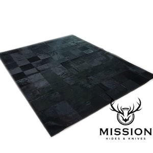 May include: Black leather patchwork rug with a chequered pattern. The rug is made of many different pieces of leather sewn together. The rug is made by Mission Hides & Knives.
