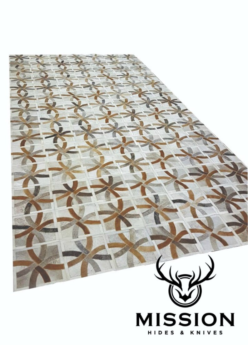 May include: A geometric patterned rug made from leather in shades of brown, gray, and white. The rug is made up of individual pieces of leather that are sewn together to create a unique design.