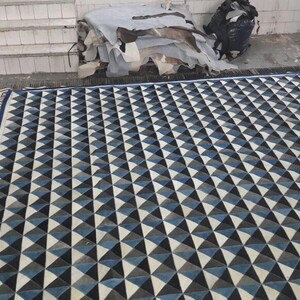 May include: A black and white geometric rug with a pattern of triangles. The rug has a blue border and is made of a soft, durable material.