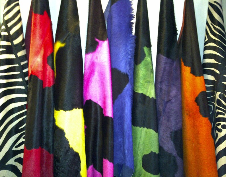 May include: A collection of colorful fabric swatches, including black and white zebra print, red and white, yellow and black, pink and black, blue and black, green and black, orange and black, and a solid black swatch.