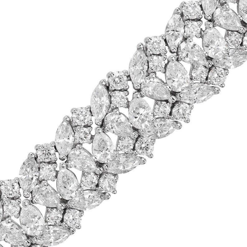 May include: A dazzling bracelet featuring a series of brilliant-cut diamonds. The bracelet showcases a mix of round, marquise, and pear-shaped diamonds, creating a luxurious and eye-catching design. The diamonds are set closely together, maximizing their sparkle.