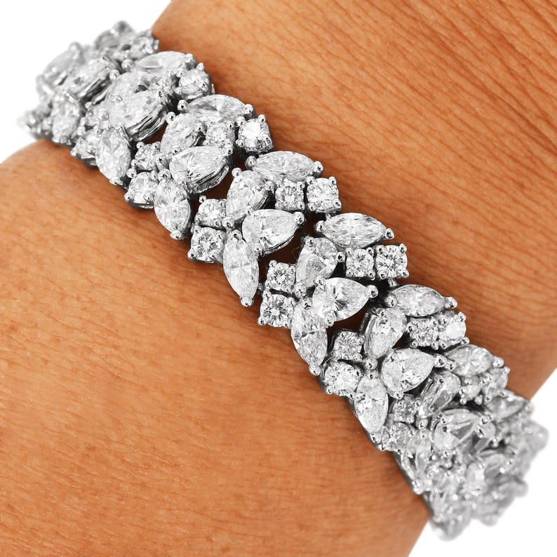 May include: A dazzling bracelet featuring a series of marquise and round-cut white gemstones. The gemstones are set closely together, creating a continuous, sparkling band. The bracelet is shown on a person's wrist.