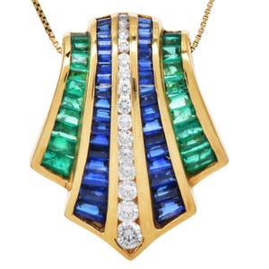 May include: A gold pendant necklace featuring a fan-shaped design. The pendant is adorned with emeralds, sapphires, and diamonds. The gemstones are set in a gold frame, creating a striking contrast of colors and textures. The necklace is a piece of fine jewelry.