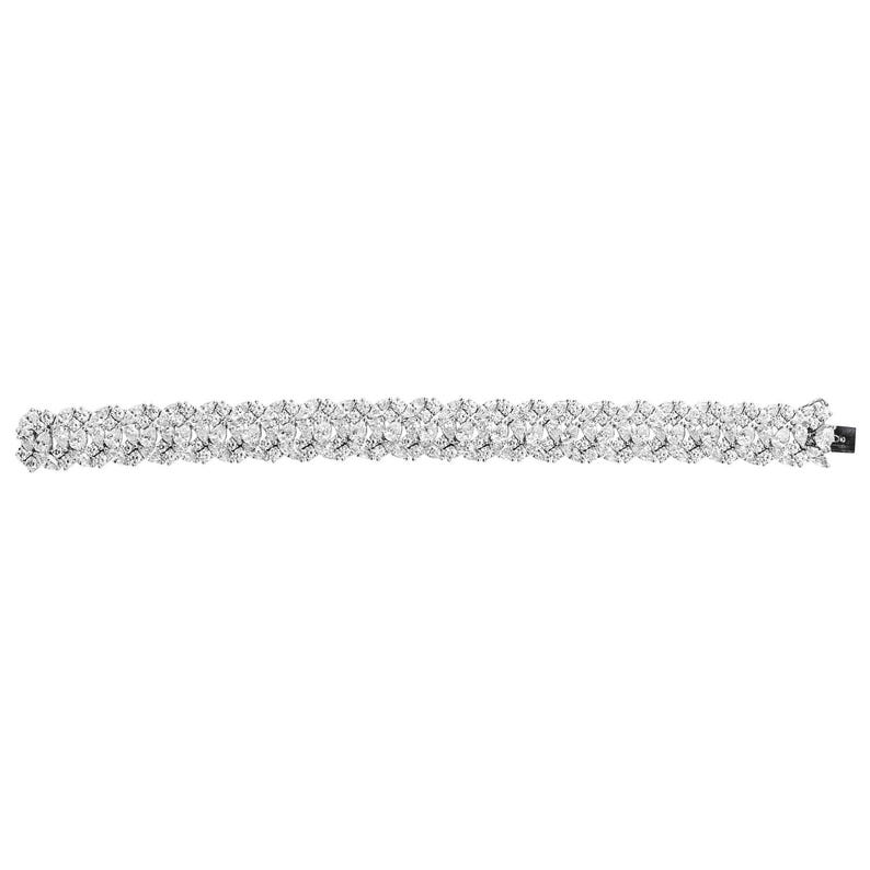 May include: A silver-toned bracelet with a double-row design. The bracelet is adorned with numerous clear, sparkling stones, creating a continuous, shimmering pattern. The clasp is a small, dark rectangle.