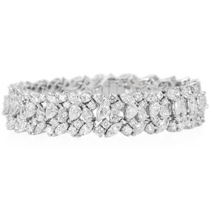May include: A dazzling, silver-toned bracelet featuring a double-row design. The bracelet is adorned with numerous clear, sparkling gemstones in various shapes, including marquise and round cuts. The overall design is symmetrical and elegant.