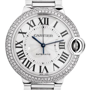 Puede incluir: Un reloj Cartier Ballon Bleu plateado con un bisel engastado con diamantes y una esfera blanca. El reloj presenta marcadores de hora en n&uacute;meros romanos, una aguja de acero azul y las palabras "Cartier" y "Automatic" impresas en la esfera.