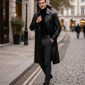 May include: A black leather trench coat, black turtleneck, and dark gray trousers. The coat is buttoned at the top and worn over a black turtleneck. The trousers are paired with black dress shoes. The outfit is completed with a black belt.
