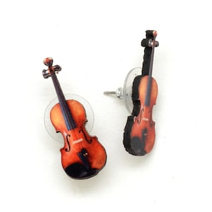 May include: A pair of violin-shaped stud earrings. The earrings feature a detailed design with a brown body, black accents, and a dark brown neck. The earrings are set on clear plastic posts.