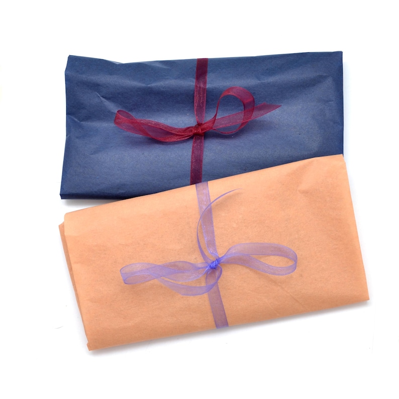 Pode incluir: Dois presentes embrulhados, um em papel azul marinho e outro em papel cor de p&ecirc;ssego. Cada um &eacute; amarrado com uma fita transparente, uma bord&ocirc; e outra lavanda. Os presentes est&atilde;o dispostos sobre um fundo branco.
