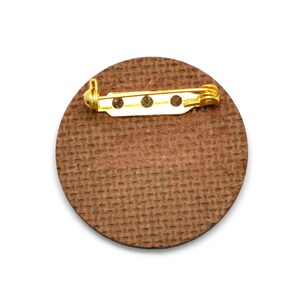 The backside of this laser cut pin show the recycled pressed wood board. The color is brown.