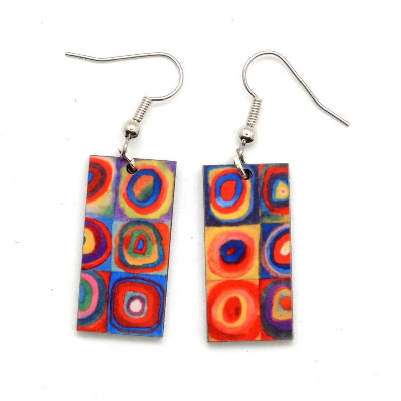 Each earring has squares, that are filled with circles. They are created with imperfect circles in a rainbow of colors including orange, red, blue, yellow, purple and green. This is from a famous painting by Kandinsky.